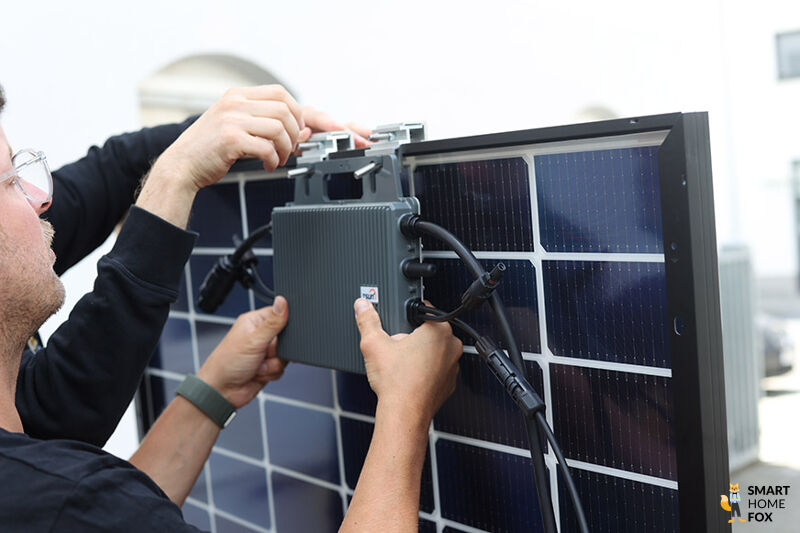 Der TSUN Balkonkraftwerk Wechselrichter wird im Test an die Rückseite des Solarmoduls an dem Rahmen befestigt.